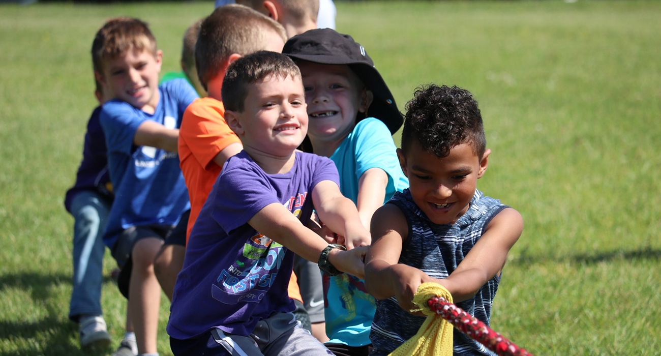 several elementary students pulling a rope in a tug of war competition